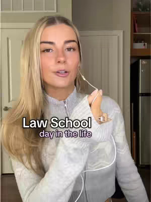 The cover image features a young woman with blonde hair, a light-colored sweater, and a neutral background composed of a white door and wall. Text overlay in a bold, sans-serif font reads
"Law School day in the life". The woman is looking at the camera and her earbuds are positioned. The lighting is bright and suggests an indoor setting.