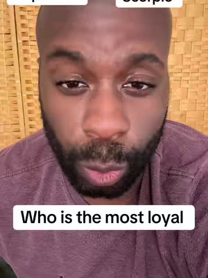 A close-up shot of a man's face. He has dark skin, a bald head, and a full, dark beard. The background is a tan, wooden textured surface, possibly a wall or a screen. Overlaid on the image are text boxes at the top and bottom: one displaying phrases, and the other asking a question.