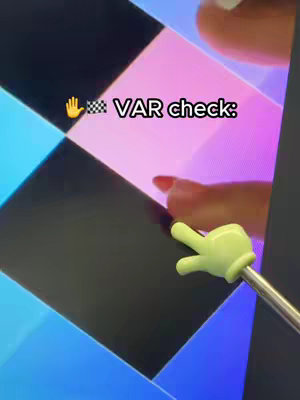 The cover image shows an angled shot of what appears to be a mobile game screen, with alternating black and colored squares. A hand-shaped pointer with a finger gesture is in the foreground. The hand is light green and the background features a woman's hand with red nail polish.