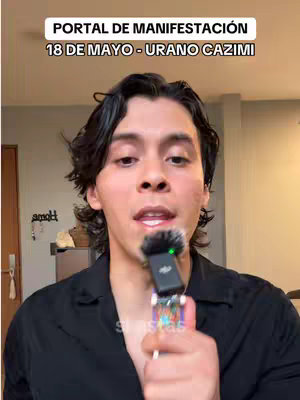 A man with dark hair holds a microphone close to his mouth, with an overlay of text at the top.