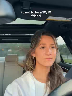 A woman is driving a car, seen from the inside. She is looking forward with a serious expression. The overhead view shows the car's interior and the road ahead.