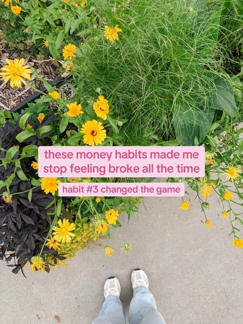 A person's feet and lower legs are visible, standing on a concrete surface. The ground is surrounded by lush greenery, with various blooming flowers. A pink rectangle with white text floats near the feet.