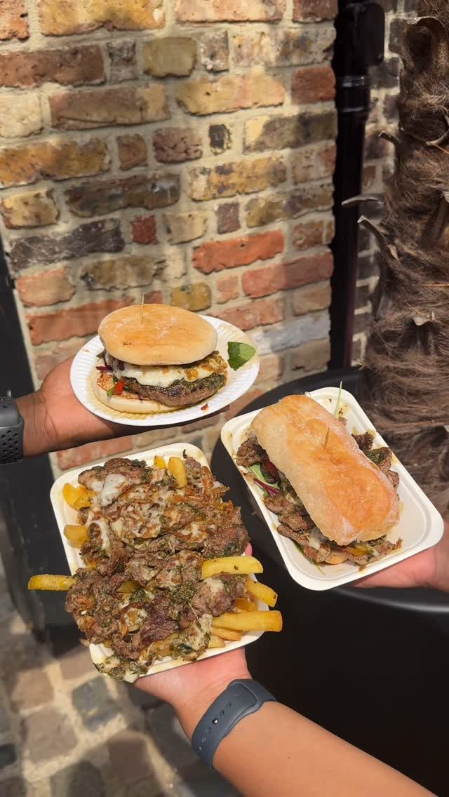 The cover image showcases three servings of food held up by three hands. The food items are Argentinian-style items. The background is a brick wall.