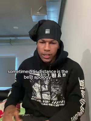 A young man in a black hoodie and beanie sits indoors, facing the camera. Text overlayed on the image reads, 'sometimes it's distance is the best apology.' The background is blurred, suggesting a casual setting.
