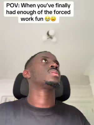 A man is looking up with a stressed expression. He's sitting in an office chair against a blurred background suggesting a home office setting. Text overlayed at the top indicates the video is about the feeling of being tired of forced work fun.