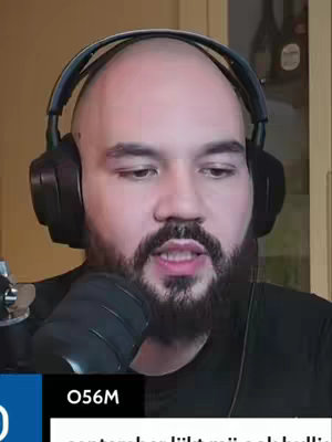A close-up shot of a man with a shaved head and full beard, wearing headphones, and looking directly at the camera. Below him is a black and blue panel with text.