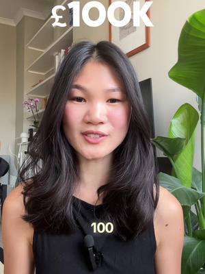 A woman with dark hair looks directly at the camera. She is wearing a black tank top, and a microphone is clipped to it. Above her head, the text "£100K" is superimposed. The background shows a light-colored wall, a bookshelf, and a large green-leafed plant.