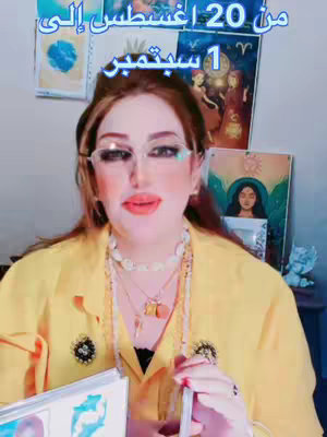 A woman with long brown hair and wearing glasses, a yellow top, and multiple necklaces is looking at the camera and holding tarot cards. Text in Arabic is overlaid at the top.