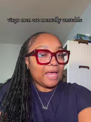 A woman with dark braided hair and large red-framed glasses speaks directly to the camera, with the overlay text "virgo men are mentally unstable". The background includes a plain wall and some shelves.
