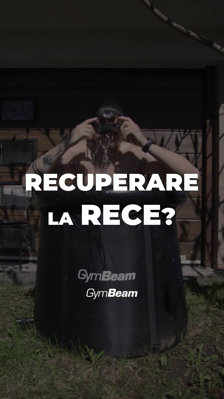 A man is taking an ice bath sitting in a black circular container. The man is wearing sunglasses and is looking up, with visible water splashing out from over his head. The container is outside, surrounded by greenery, and the words “RECUPERARE LA RECE?” are written in white over the image.