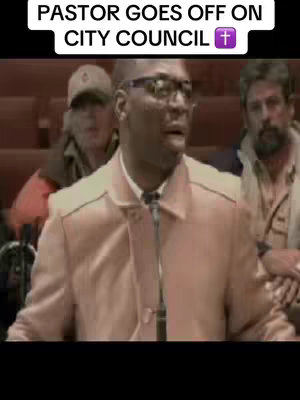 The cover image shows a man speaking into a microphone in front of a group of people. Text overlays the top, identifying the speaker as a pastor. The scene is set in what appears to be a public meeting or city council.