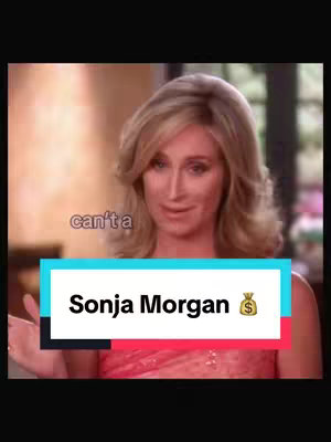 A still image from a video. A woman with blonde hair is staring into the camera, framed from the chest up. She is wearing a red dress. The overlay includes a rectangular box containing the text "Sonja Morgan" and a money bag emoji. Overlaid text in the corner reads "can't a". The background is blurred suggesting an indoor setting.