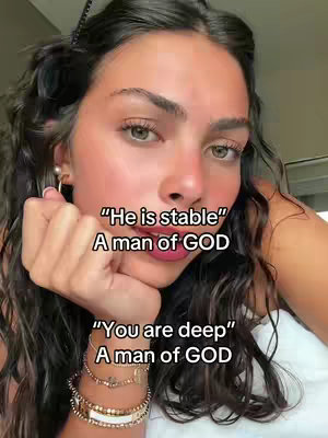 A selfie-style shot featuring a woman with long, wavy dark hair, gazing at the camera with a thoughtful expression. She is wearing jewelry, including a gold earring and bracelets. Text overlays are positioned at the upper and the lower center of the frame.