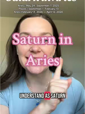 A selfie-style video cover image features a woman with brown hair and a blue shirt, with the text overlay 'Saturn in Aries' in a pink, outlined font, situated over her face. Below, next to her index finger is text, 'UNDERSTAND AS SATURN'. The image includes superimposed text related to astrological dates, arranged on a light background.