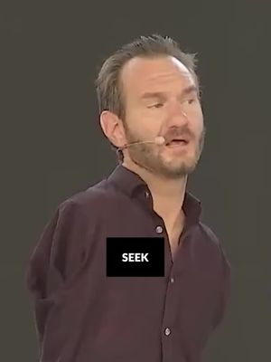 The image shows a man giving a speech, the man is the primary focus. He has short, light-brown hair and a beard. He is wearing a dark purple button-down shirt, and a microphone is positioned near his face. A black rectangular text overlay with the word "SEEK" is prominently displayed over his shirt.