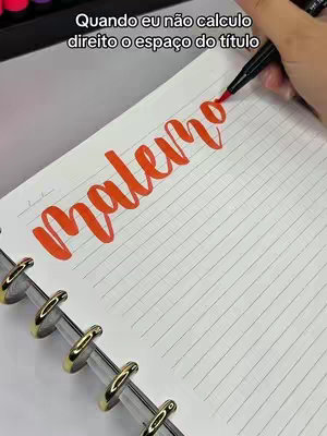 The cover image shows a close-up of a person's hand writing in a notebook. The word "Maleno" is being written with a red marker. The text overlaid on the image says 'Quando eu não calculo direito o espaço do título', indicating that the person is making a title for a study with mistakes