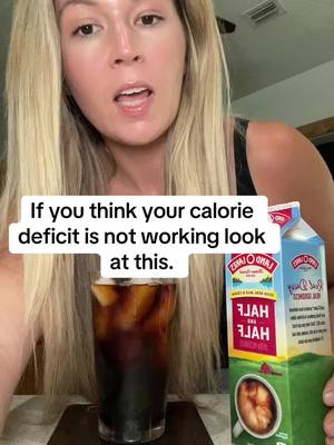 A woman with blonde hair is holding a carton of Half and Half, a glass of iced coffee, and making a direct statement to the camera. Overlay text gives context to the content.