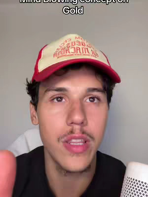 The video shows a close-up of a young man wearing a red and white trucker hat. The man has short dark hair, a mustache, and is looking directly at the camera; his face takes up most of the frame. The background is a plain gray wall. The text overlay at the top reads "Mind Blowing concept on Gold". The image is well-lit and focused on the man's face.