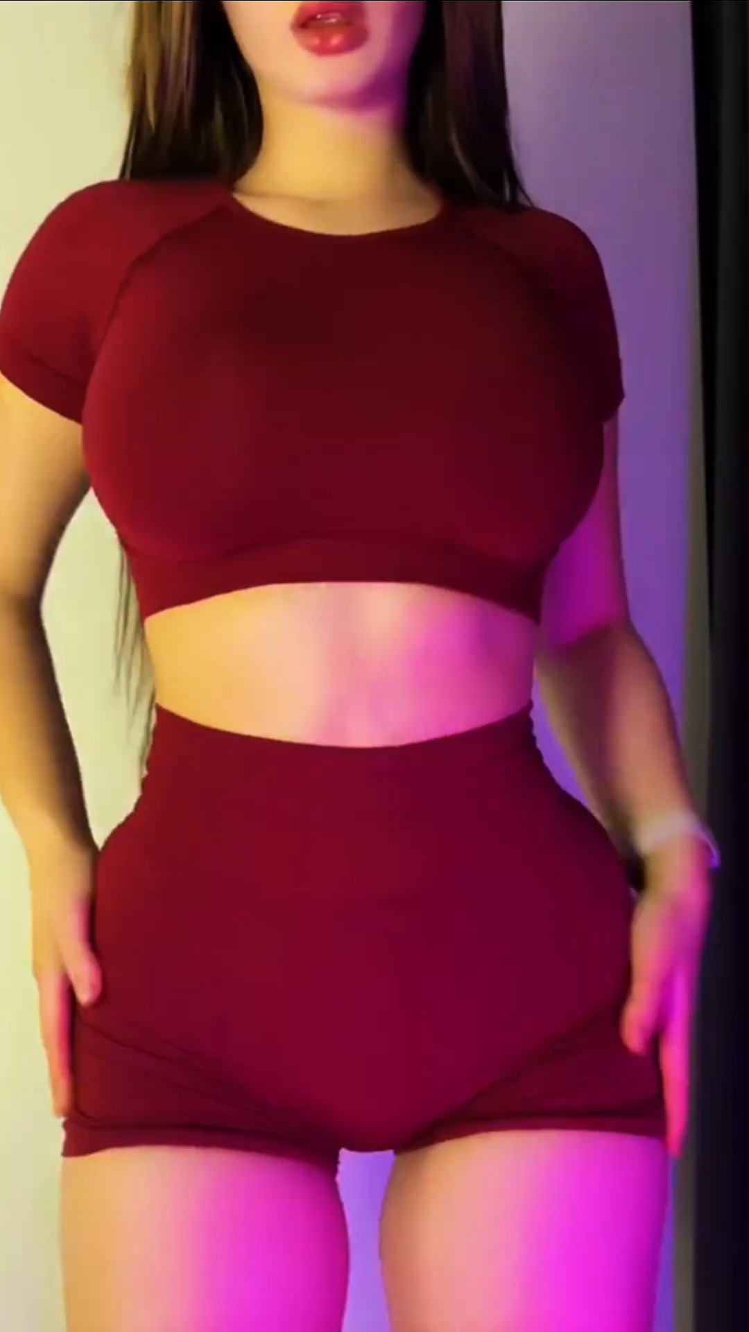 The cover image shows a person from the chest down, wearing a maroon athletic top and shorts. The person is standing with hands on hips, and the background has purple and yellow lighting on both sides. The pose conveys confidence and fitness.