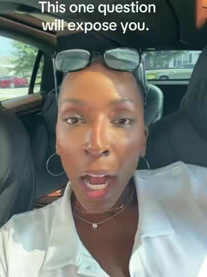 A selfie-style shot of a woman inside of a car. She has glasses on her forehead and is looking directly at the camera with her mouth open. The background shows parts of the car and surrounding environment.