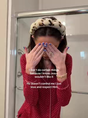 A woman in a red, patterned top stands in what appears to be a bathroom, covering her face with both hands. Overlaid text provides the video's message.