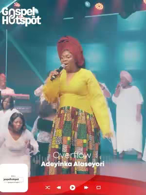 A woman in a yellow dress and patterned skirt sings into a microphone on a stage with other people and a band in the background. Text overlay indicates, "Overflow" and "Adeyinka Alaseyori". The scene is lit with stage lighting in a teal and red theme, indicating an African Gospel music performance.