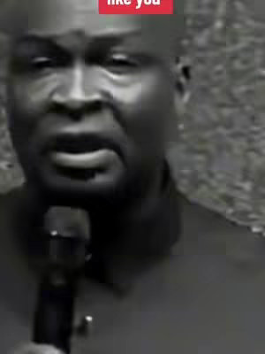 A grayscale video still of a man with a microphone, presumably speaking or making a presentation. The image is a close-up of the man's face. The subject is an adult male with short hair. Above the man's head is a red text overlay that reads: "like you."