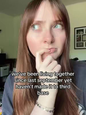 A woman with long brown hair and a nose ring, the woman is looking off camera with her fingers near her mouth and a thoughtful expression on her face. Text overlayed on the image.