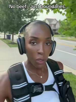 A woman with short hair wearing large black headphones and a weighted vest walks towards the camera on a sunny day. Text overlay reads "No beef. Just boundaries.". The background shows houses, trees, and a road suggesting an outdoor walking environment.