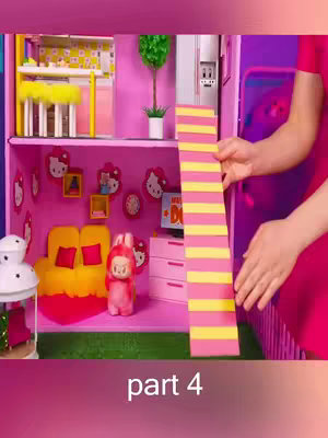 A miniature dollhouse scene is presented. The interior walls are pink, and the set is furnished with miniature furniture. The primary elements include a pink doll figurine, a yellow couch, and a decorative strip with alternating pink and yellow stripes.