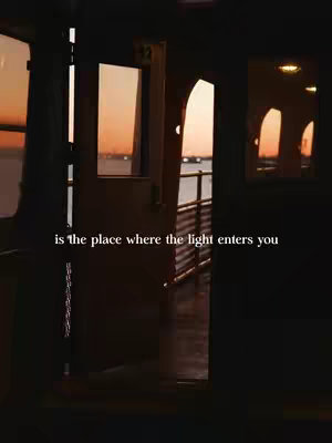 A dim interior scene, likely a boat or building, at twilight. The foreground shows interior details, including a door frame and arched opening. Through the openings, an orange and pink sunset is visible over the water. Text is overlaid at the bottom.