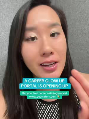 The cover image is a selfie-style shot. The foreground features a woman with dark hair and fair skin, centered and looking directly at the camera. The woman's face is well-lit, revealing details like her makeup and expression. The woman is wearing a black and white patterned top. The background is a plain, light gray wall. In the bottom third of the image, two horizontal text boxes are overlaid. The upper box is turquoise-blue and contains white text "A CAREER GLOW UP PORTAL IS OPENING UP." Below it, there is a smaller, dark green box with the words "Get your free career astrology report" and the web address, "www.yoursaturn.com".