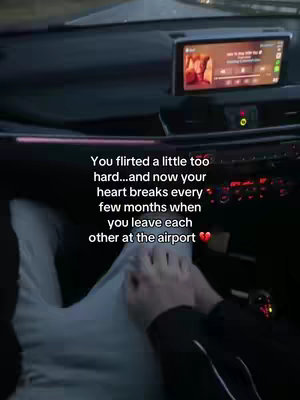 An interior car shot with a focus on the lower body and hands. Text overlayed on the lower right corner describes the emotional dynamics of a long-distance relationship.