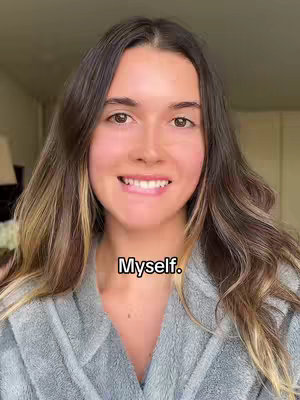 A woman with long brown hair and a gray robe smiles directly at the camera. The image has warm lighting with some of the background blurred out, and the text overlay "Myself." is positioned near the bottom.