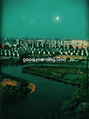 An aerial view of a city at dusk, with a river and greenery in the foreground and a cityscape in the background. The sky is a teal color.