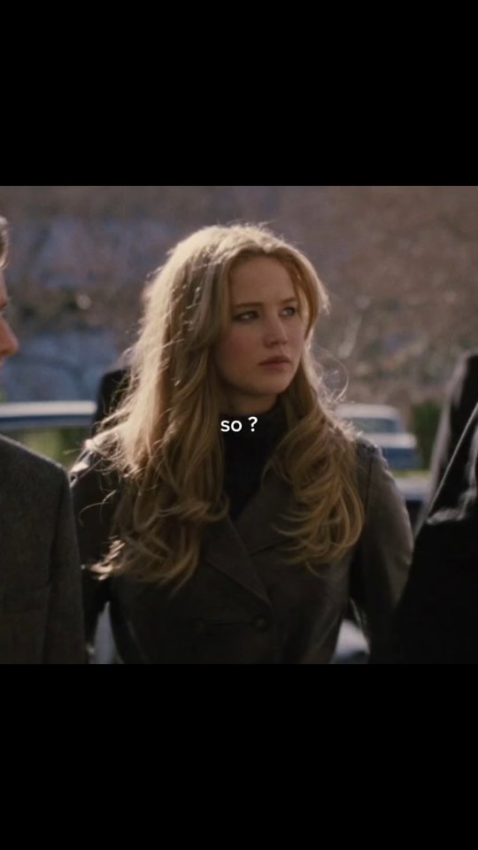 The cover image is a still from a movie. The main subject is a woman with long blonde hair looking off to the side. The image is softly lit and has other people in the background, the image is partially cropped from the left and right.