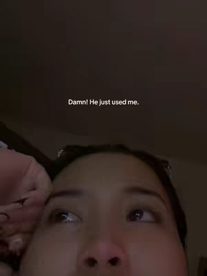 A close-up selfie centered on a young woman's face. Her eyes are focused upwards with a slight watery sheen, suggesting tears or impending tears. Over all, the dark lighting emphasizes the emotional state. The background is a blurred dark ambience.