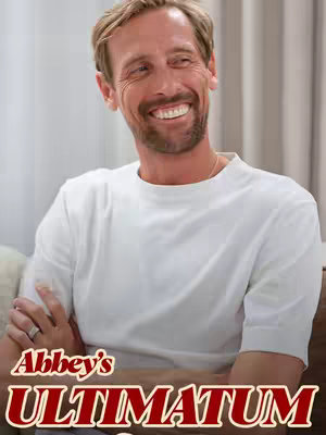 A medium shot features a man smiling, lit with soft, even lighting. He wears a white t-shirt, and his right arm is slightly bent. Below him, text reads "Abbey's ULTIMATUM".