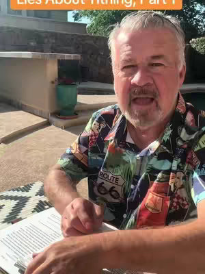 A man with gray hair and a beard speaks towards the camera, sitting at a table with a book. He wears a colorful short-sleeved shirt. In the background, there is a patio with a plant and a pool.