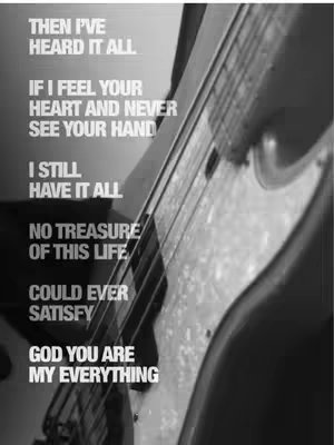 A striking black and white image featuring the partial view of a guitar, its strings and body dominating the frame. Superimposed on the guitar are vertical lines of white text, forming a poem about love and devotion. The composition is stark, with a strong contrast inherent in the black and white colour palette and the sharp lines of the guitar are contrasted against the smooth body.