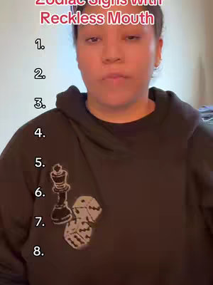 A medium shot features a woman centered in the frame, posing against a neutral background. Her skin has a warm complexion, and her dark hair is pulled back. She wears a black hoodie with a white design on the chest. The image is lit evenly, and the background is plain. The top of the image has text overlayed in red. Below, numbers are listed in white.
