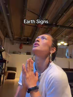 A person with their hands clasped in prayer. The person is looking up with their eyes closed. The background has exposed pipes.