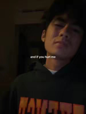 The cover image features a young man in a close-up shot, slightly off-center. He wears a black hoodie with a design near the bottom and has a black cap. The lighting is dim, creating a moody atmosphere. Text overlayed in the image reads, 'and if you hurt me'.