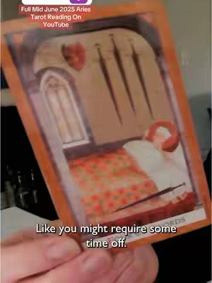 The image shows a tarot card held against a background. The card depicts a room with a bed and a figure, along with related text in the image. The colors are muted, with a focus on the detail of the card's design.