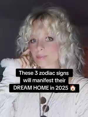 A woman with curly blonde hair, touching her face, is the central focus. Text overlay in a black rectangle proclaims a message about zodiac signs, manifestating a dream home in 2025. The background is dark.