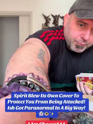 The image features a man with a beard and a backwards cap, angled partly towards the camera. The man is wearing a black t-shirt with red stripes, and holding a card in his right hand. A tattoo is visible on his left arm. Overlayed on the image is a blue rectangle of text with the title of the video.