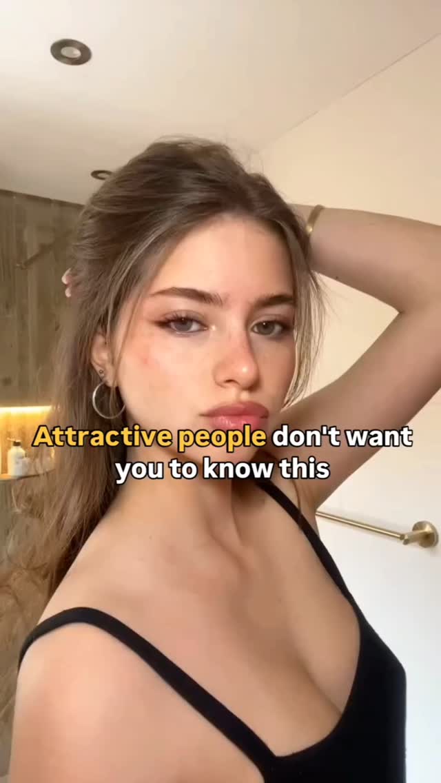 A young woman with long light brown hair, gently pulled back in a casual updo is looking at the camera with a neutral expression. She is wearing a black tank top. Text overlayed in yellow reads "Attractive people don't want you to know this".