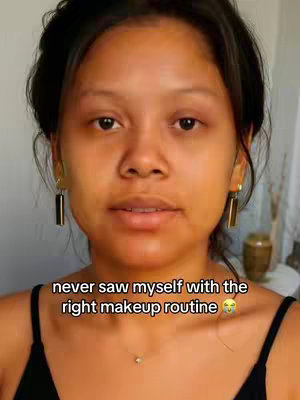 A woman with dark hair and fair skin looks directly at the camera. The foreground is the woman's face and upper body. She appears to be makeup-free, with dark eyes, and wearing dangling earrings. The background is a neutral color. Text overlayed on the image provides context for the video.