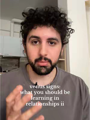 A man with dark curly hair and a beard is centered in the frame, set against a blurred background. The man is wearing a gray shirt, and the text overlayed on the image reads, 'venus signs: what you should be learning in relationships ii'. The composition is focused on the man's face and upper body.