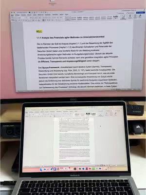 A person is using two screens to study, with text from a document on the larger screen, and a laptop displaying the same text below. The photo is well-lit and organized, focusing on the devices used for academic work.